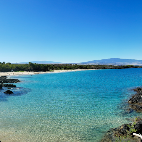 Paddle in the clear waters on Hapuna Beach, a thirteen-minute drive away