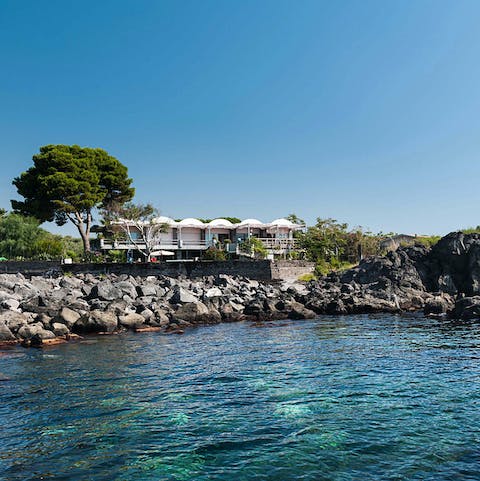 Admire the striking architecture of your modern villa from a boat on the water
