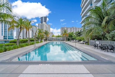 Cool off in the communal pool framed by palm trees and city towers