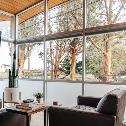 Kick back on the armchairs while enjoying stunning natural views from the wall of windows