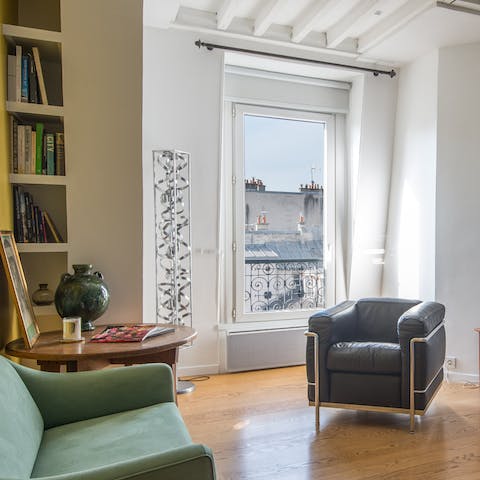 Perch by the living room's Juliet balcony with a glass of wine while admiring Paris rooftop views