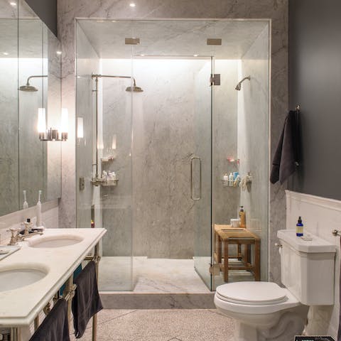 The dual shower heads in this marble bathroom