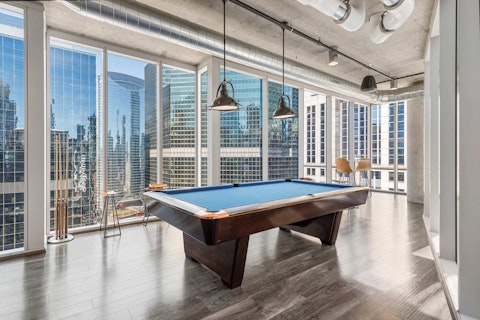 Shoot pool in a sky-high games room with the city spread below