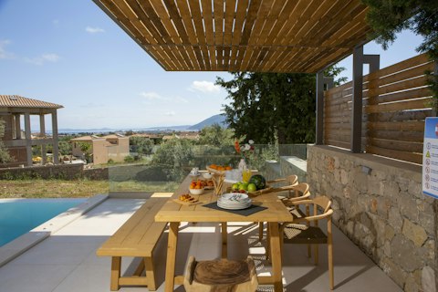 Dine beneath a slatted pergola with distant sea views