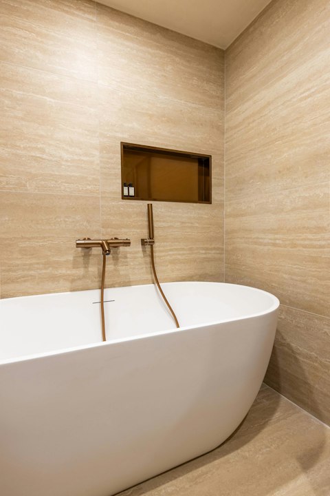 Unwind in a warm, travertine-tiled bathroom with a deep bathtub