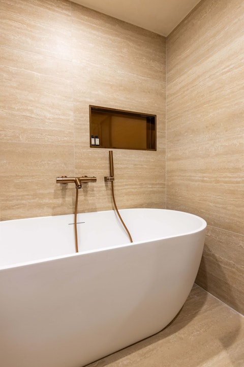 Unwind in a warm, travertine-tiled bathroom with a deep bathtub