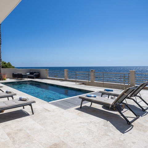 Lounge by the pool with a beachfront view front and centre