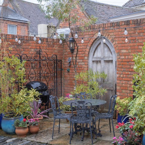 Take a seat beneath the strings of lights in the walled garden