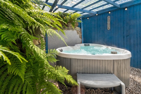 Unwind in the bubbling hot tub beneath fairy lights and ferns
