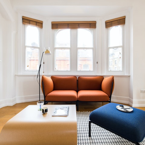 Relax in a living room with plenty of sunlight from the bay windows