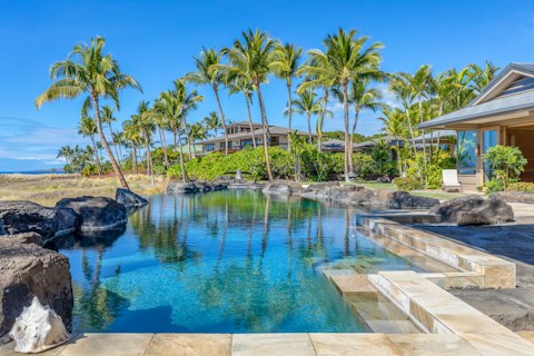 Swim in a pool framed by volcanic rock and palm trees
