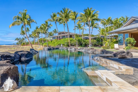Swim in a pool framed by volcanic rock and palm trees