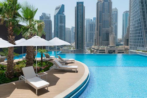 Relax by the glistening infinity pool with the unforgettable view of towering skyscrapers