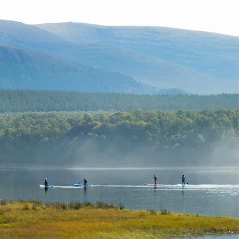 Enjoy paddle-boarding on Loch Insh, a nine-minute drive away
