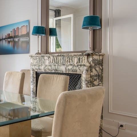 Gather around the dining table next to traditional features like the marble fireplace