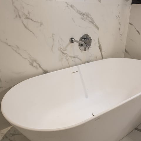 Have a soak in the freestanding tub in the luxurious marble bathroom