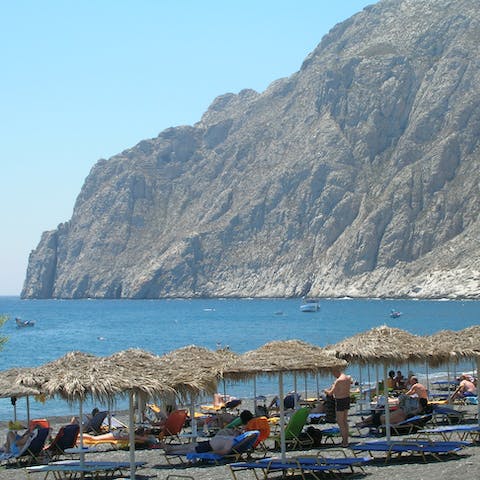 Witness the unique beauty of the black, volcanic sands of Perivolos Beach, just a 13km drive away