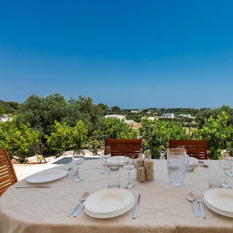 Clink glasses of local Manzoni bianco at the dining table by the olive grove
