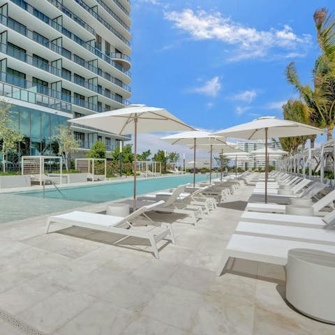 Relax on a sun lounger by the building's swimming pool