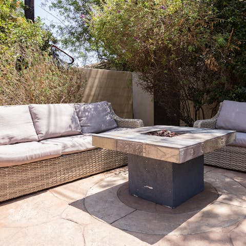 Chill out around the fire pit at the palm clad, cosy outdoor living area