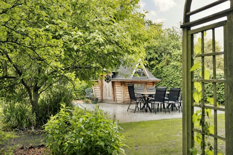 Dine alfresco beneath mature trees in the verdant garden