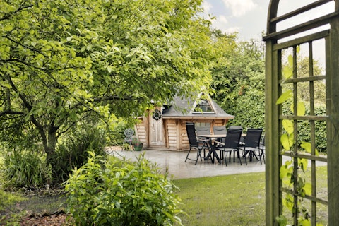 Dine alfresco beneath mature trees in the verdant garden