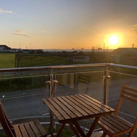 Enjoy sundown drinks on your private balcony with distant sea views